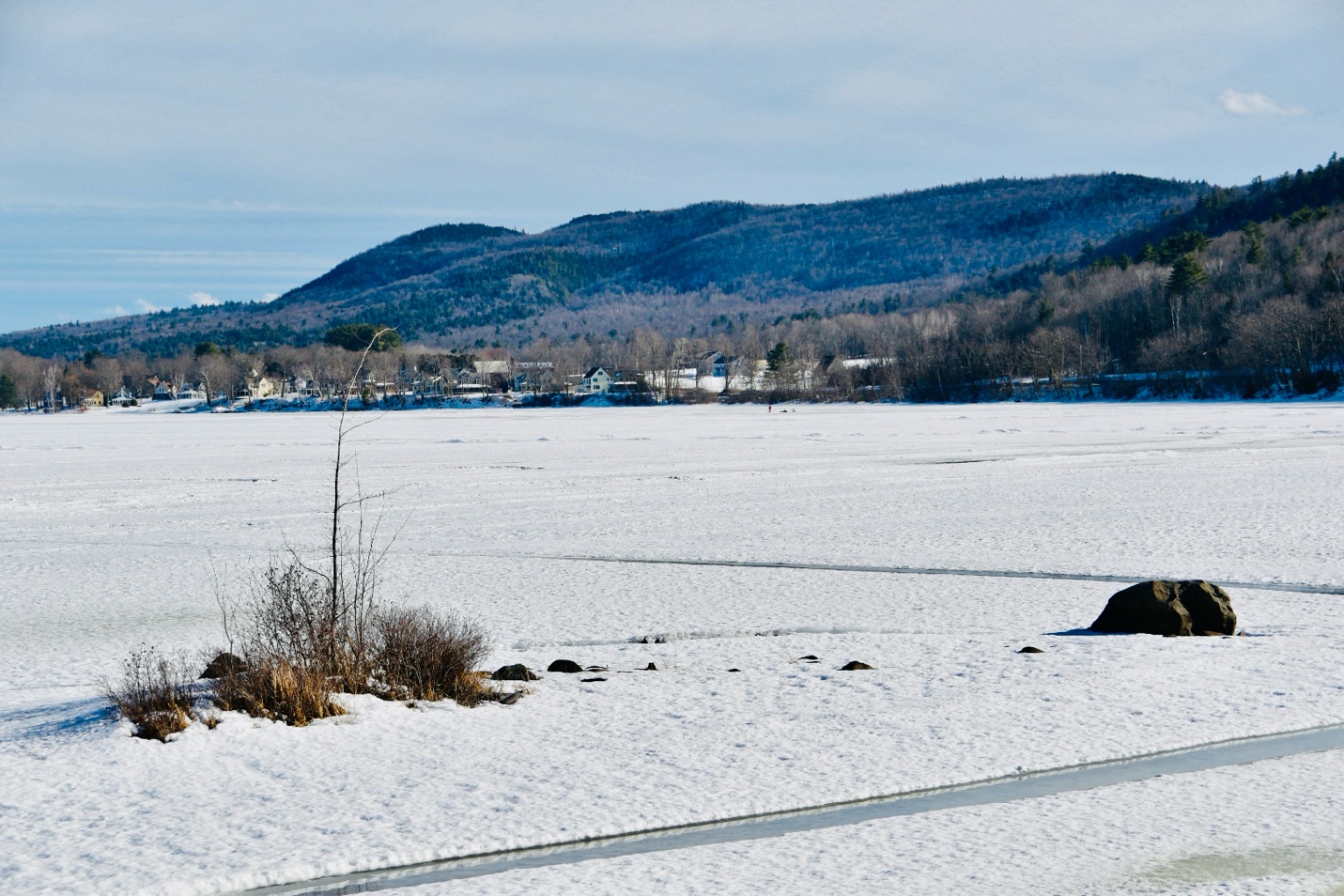 Frozen lake with distant mountains and a small village